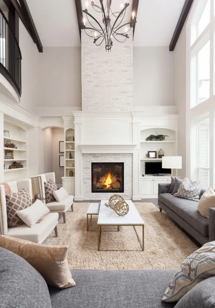 Living room with white brick fireplace, gray sofas, and vaulted ceiling