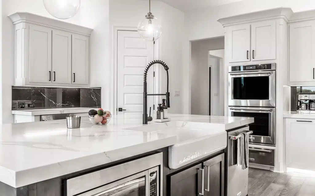 White kitchen with marble island, black fixtures, and stainless steel appliances