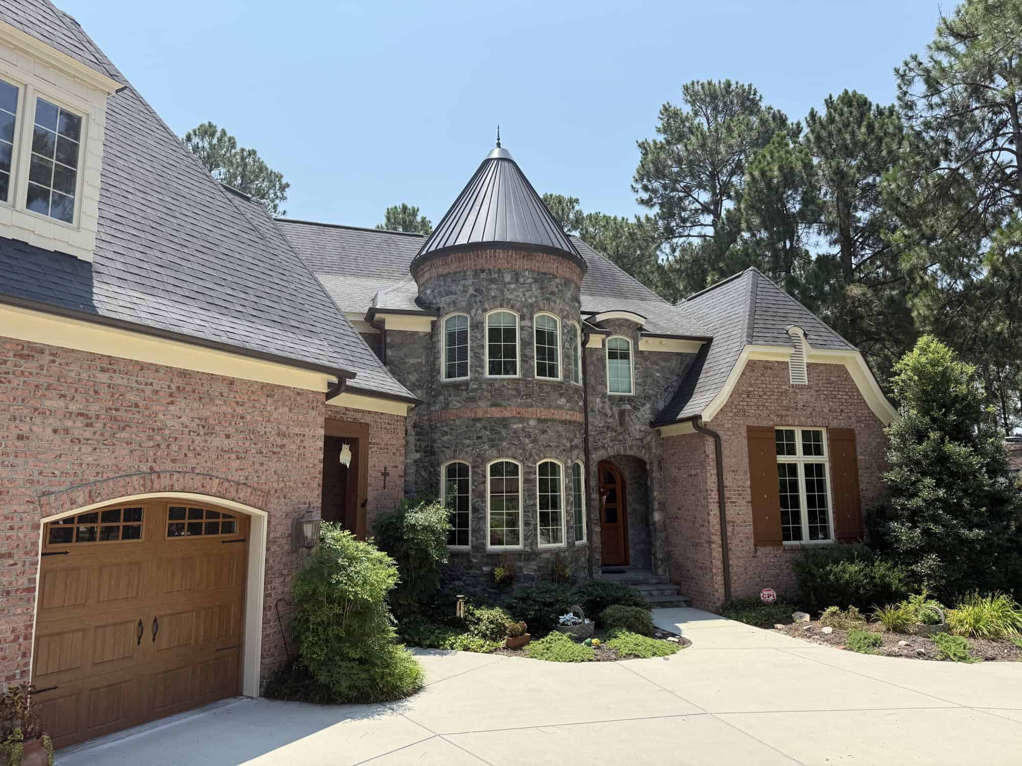 Brick and stone luxury home with round turret entrance and wood garage door