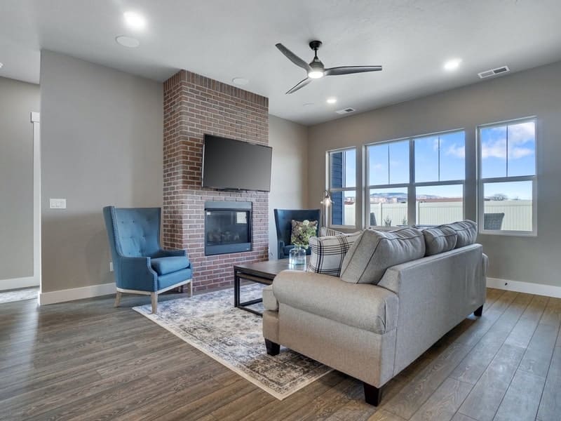 Living room with brick fireplace, blue accent chairs, and gray sofa