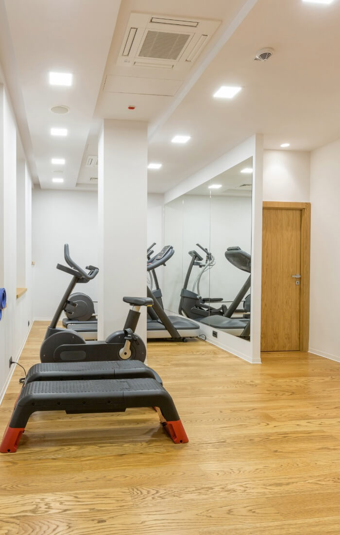 Small gym room with exercise bikes, step platform, and mirrored wall