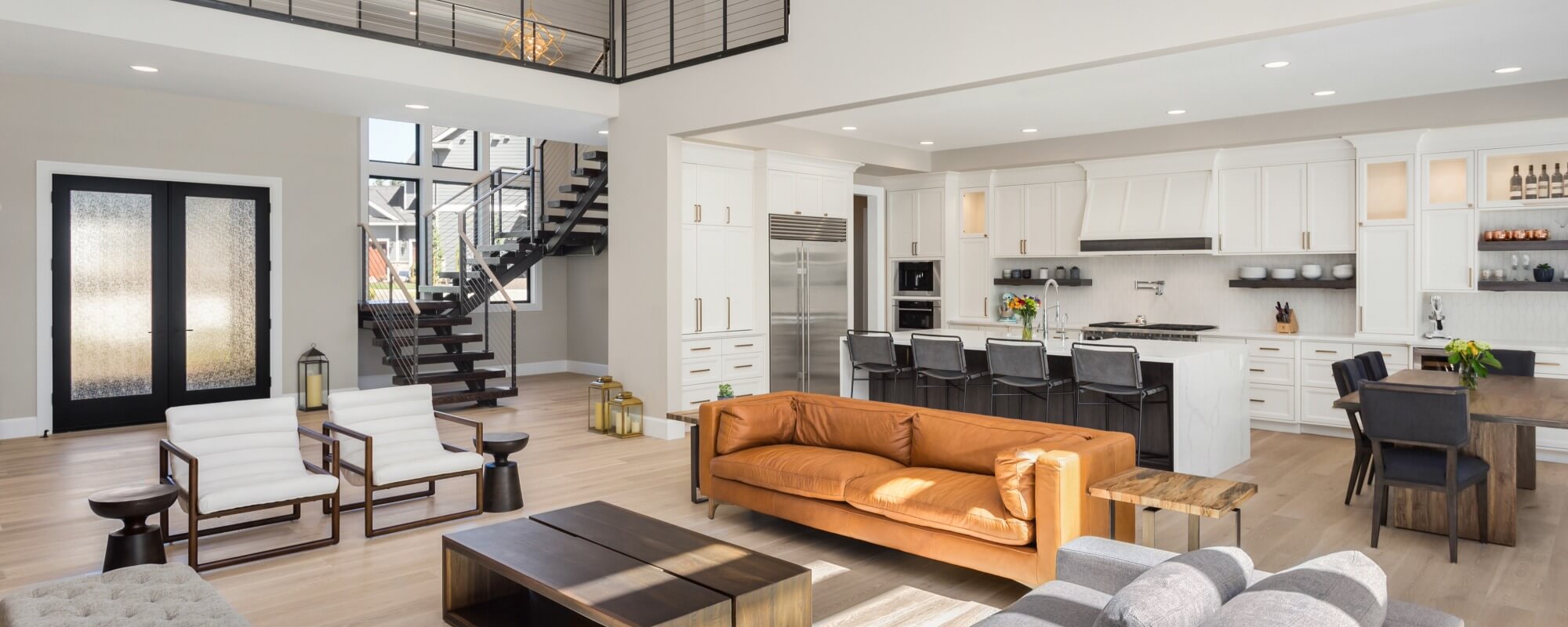 Open-concept living room, kitchen, and dining area with white cabinetry and wood floors
