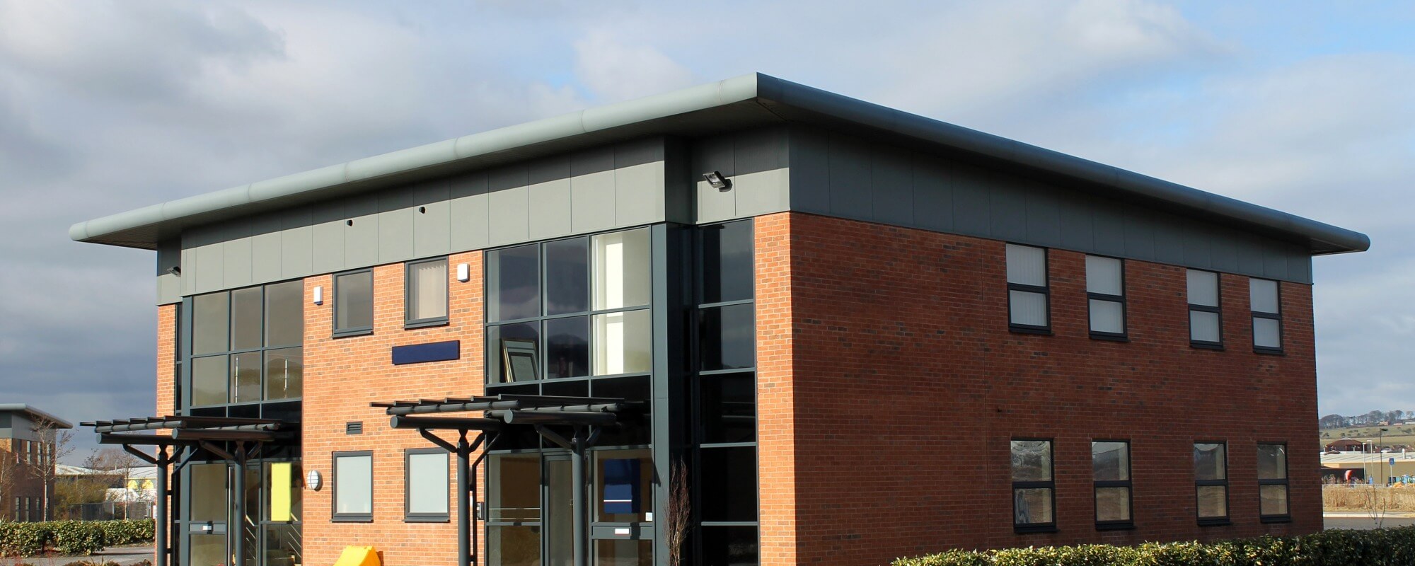 Two-story brick commercial office building with dark gray trim and large windows