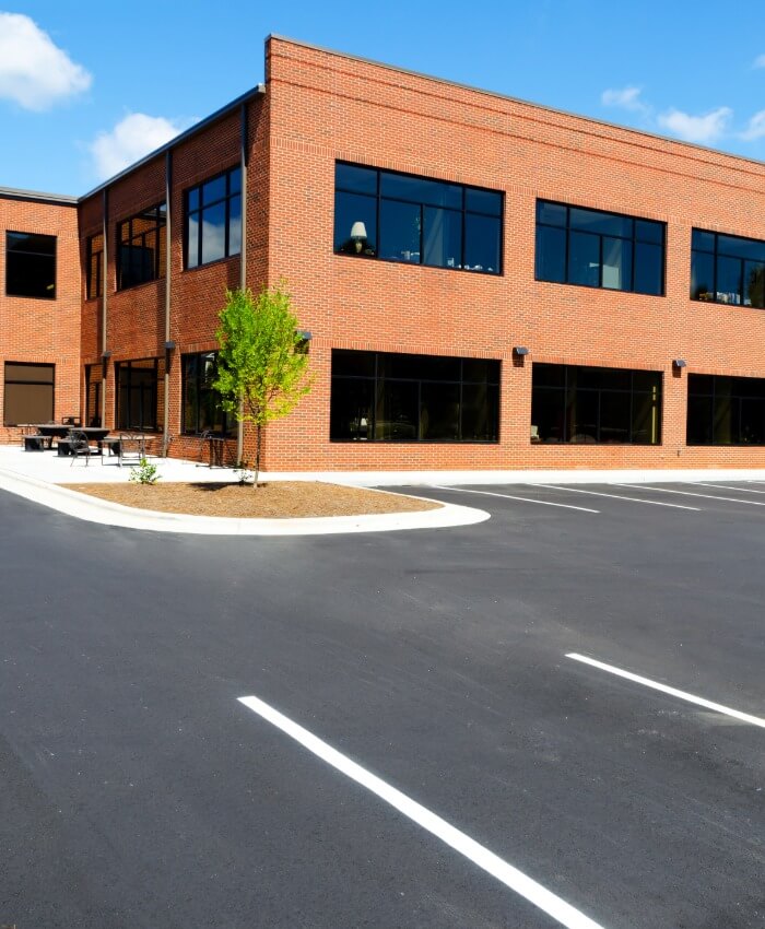 Two-story brick office building with large windows and paved parking lot