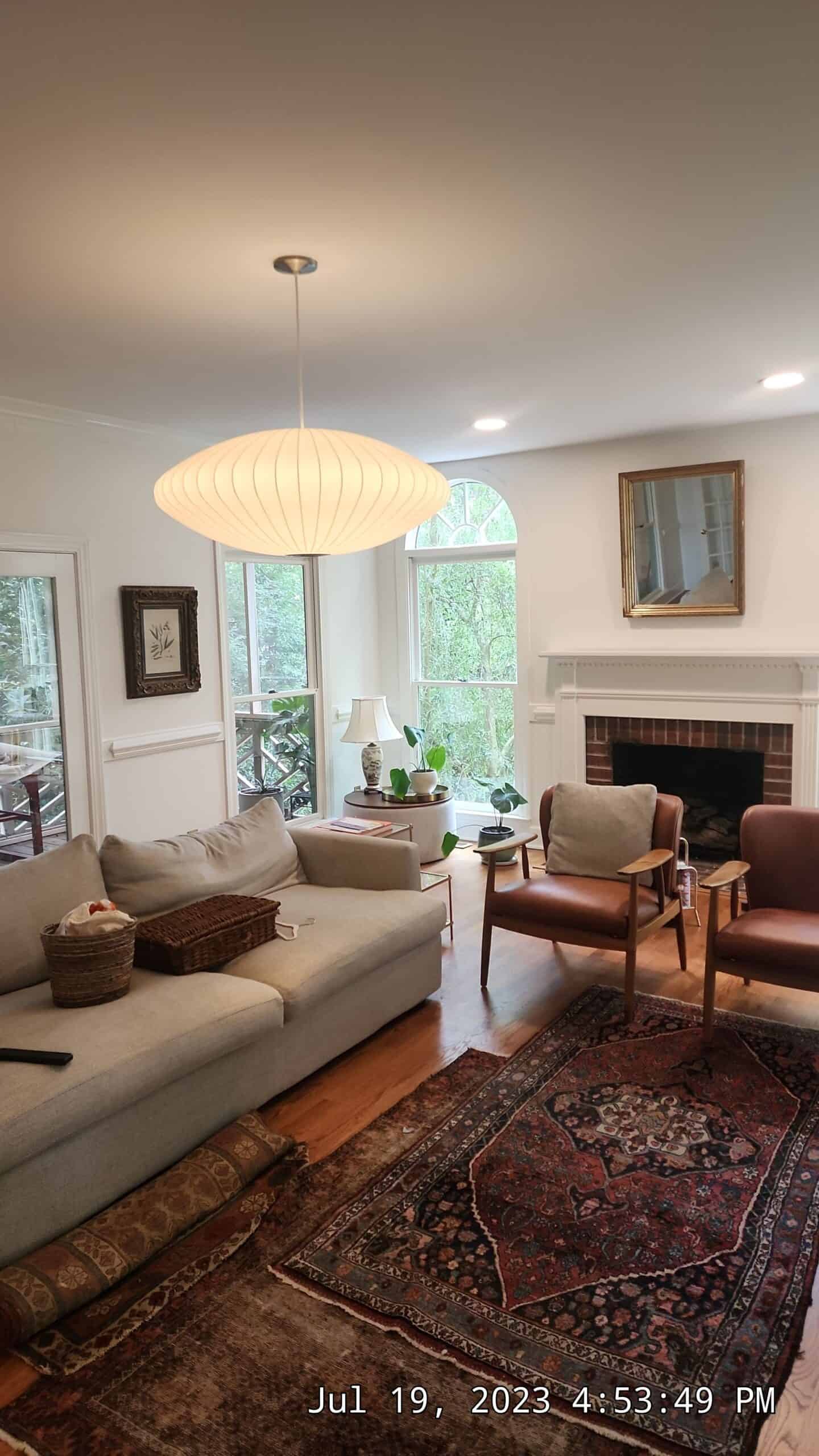 Living room with brick fireplace, white walls, and patterned area rugs