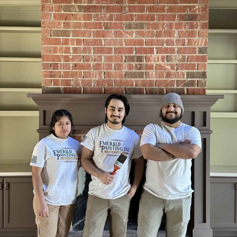 Three Emerald Painting team members standing in front of a painted mantel and brick chimney
