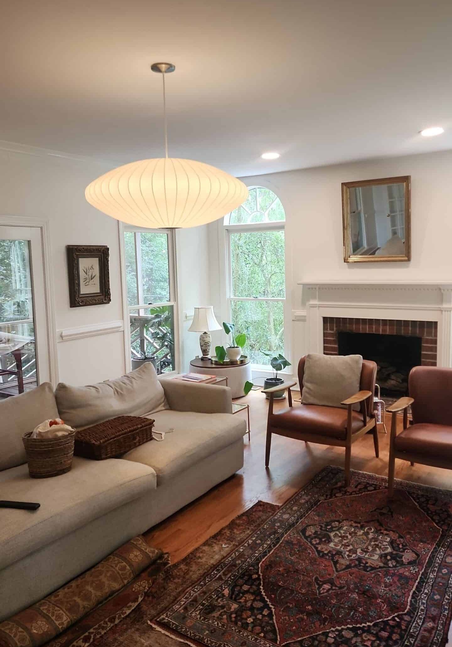 Living room with brick fireplace, white walls, and patterned area rugs